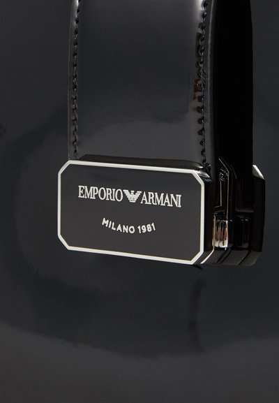 Cinturón de cuero negro con un acabado brillante, que presenta un cierre metálico y un logo grabado: "EMPORIO ARMANI MILANO 1981."