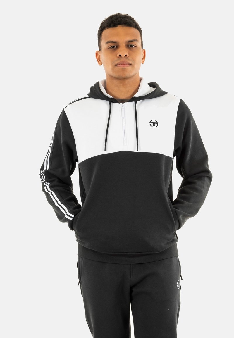 Felpa zip-up bianca e nera con colletto alto, pannello frontale a contrasto e strisce laterali. Tessuto liscio con logo sul petto.