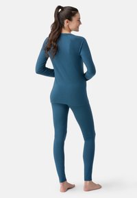 Blå langærmet top og matchende leggings lavet af blødt stof, med en tætsiddende design og sømløs konstruktion for komfort.