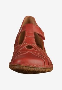 Red leather sandal featuring a closed toe, cut-out details, and adjustable strap. Textured sole with visible stitching accents.
