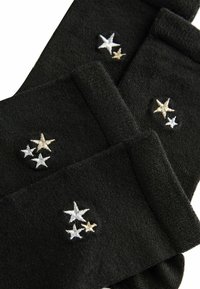 Schwarze Socken mit silbernen und goldenen gestickten Sternen. Weicher Stoff mit glatter Textur und einem gerippten Bündchen für einen eng anliegenden Sitz.