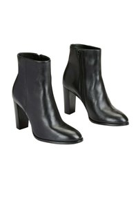 Paire de bottines noires en cuir avec bouts pointus, talons carrés et fermetures éclair latérales sur fond blanc.
