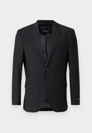 Melns žakete ar nošķeltu atloku, divām pogām un sānu kabatām. Raksturo gluda apdare un piegriezts siluets. Iekšpuse ir oderēta.