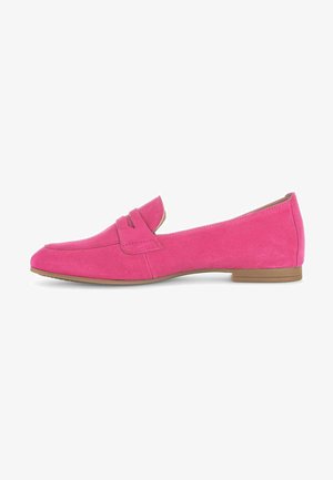 Mocassin en suede rose avec un talon plat, présentant un design cousu et un cou-de-pied rehaussé. Texture lisse et accents matériels minimalistes.