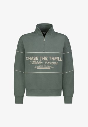 Green half-zip sweatshirt with white printed text. Features a relaxed fit, ribbed cuffs, and decorative stitching. Soft fabric texture.