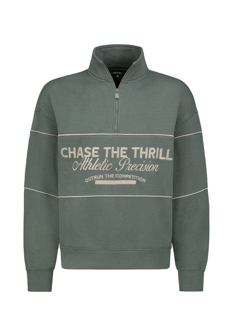 Grünes Sweatshirt mit halbem Reißverschluss und weißem Aufdruck. Verfügt über eine lässige Passform, gerippte Bündchen und dekorative Nähte. Weiche Stoffstruktur.