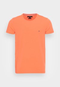 T-shirt a maniche corte con collo rotondo di un vivace arancione, realizzato in cotone con un piccolo logo sul lato sinistro del petto. Texture liscia e leggera.