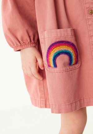 Robe en coton rose avec manches bouffantes et une poche ornée d'un motif arc-en-ciel multicolore brodé. Texture lisse.