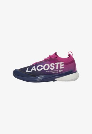 Zapatilla de running Lacoste con un upper en degradado púrpura y azul marino, gran logotipo blanco, suela texturizada y tirador en el talón.