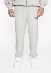 Pantalones de chándal grises de mezcla de algodón, con una cinturilla elástica y cordón ajustable, y el logo negro "MULTI" en el muslo izquierdo.