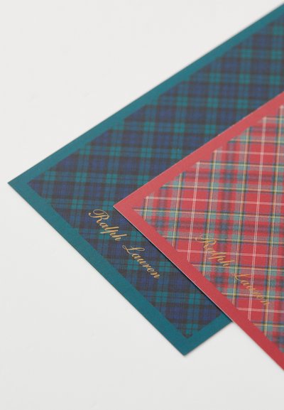 Two sheets of wrapping paper: one dark green with a blue and black plaid pattern, the other red with a classic plaid design. Both feature gold text.