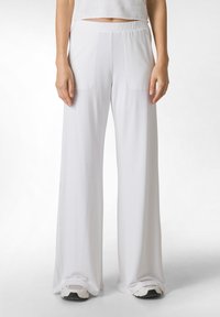 Valkoiset leveät housut, jotka on valmistettu pehmeästä kankaasta. Ominaisuuksiin kuuluu joustava vyötärö ja sivutaskut. Sujuva pinta ja rento istuvuus.