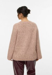 Pull en tricot rose avec une coupe décontractée, des poignets côtelés et un col rond. Texture douce avec des touches de couleur à travers.