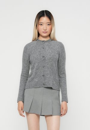 Gray knitted cardigan with a round neckline, front buttons, and long sleeves. Paired with a pleated gray skirt.