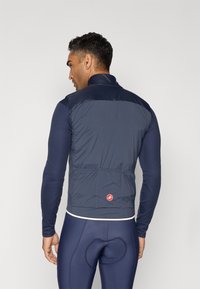 Chaleco de ciclismo de color navy con un diseño ligero y acolchado, que cuenta con un cuello alto, mangas ajustadas y un detalle de logo en la parte posterior.