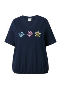Camiseta de canalé azul marino con escote en V y mangas cortas, que presenta tres flores bordadas en azul, rosa y amarillo, y un detalle de dobladillo fruncido.