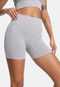 Sive atletske kratke hlače z visokim pasom, gladko teksturo in prilegajočo silhueto. Imajo minimalne šive in logotip.