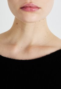 Black sweater with a wide neckline, featuring a smooth texture. Close-up focus on lips and neck with light skin tones and subtle freckles.
