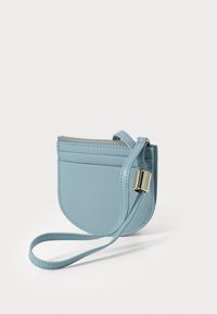 Portafoglio in pelle azzurro chiaro con finitura testurizzata, forma curvata, chiusura con zip e una tracolla rimovibile con dettagli in metallo dorato.