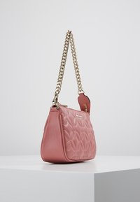 Borsa a mano in pelle rosa con motivo floreale trapuntato, tracolla in catena dorata e chiusura con zip, caratterizzata da una texture liscia e da una forma strutturata.