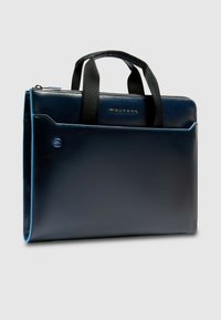 Bolso para portátil de cuero azul marino con textura suave, asas superiores y costuras en color azul; cuenta con un bolsillo frontal y cierre de cremallera.