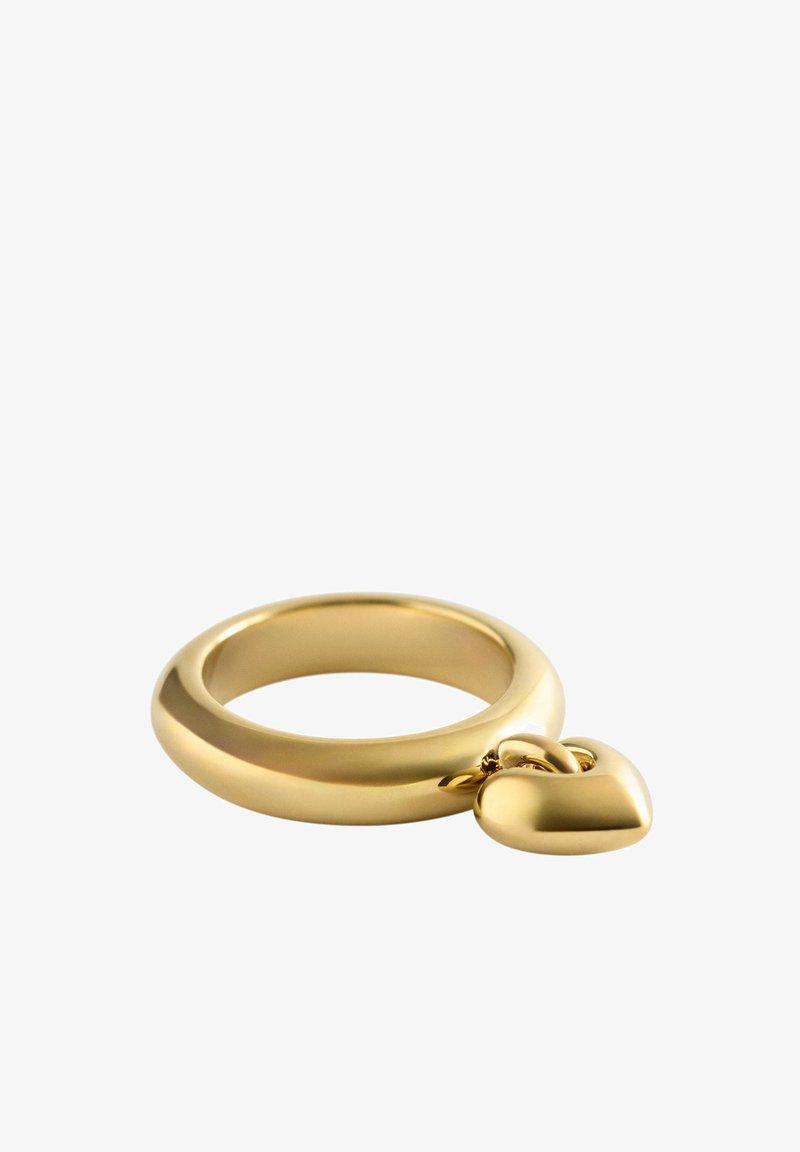 Anillo de oro con un pequeño colgante pulido en forma de corazón, exhibido sobre un fondo blanco.