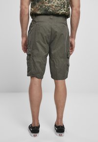 Pantaloni cargo verde oliva con vestibilità comoda, dotati di tasche laterali, dettagli cuciti e un tessuto leggero. Inclusi accenti di bottoni argentati.