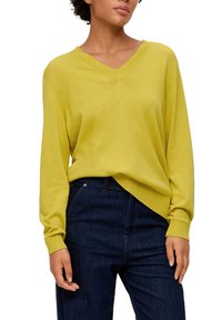 Gelber V-Ausschnitt-Pullover mit langen Ärmeln, gerippten Bündchen und lockerem Schnitt, kombiniert mit dunkelblauen Jeans. Glatte Textur, minimalistische Designmerkmale.