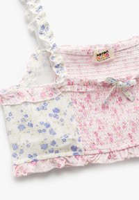 Top de patchwork floral con diseños en azul claro y rosa, tirantes con volantes y un lazo atado en la parte delantera. Hecho de un tejido ligero.