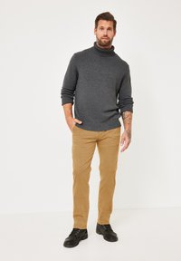 Dark gray turtleneck sweater, ribbed cuffs, paired with light tan corduroy pants and black lace-up shoes. Minimalist design, fitted silhouette.