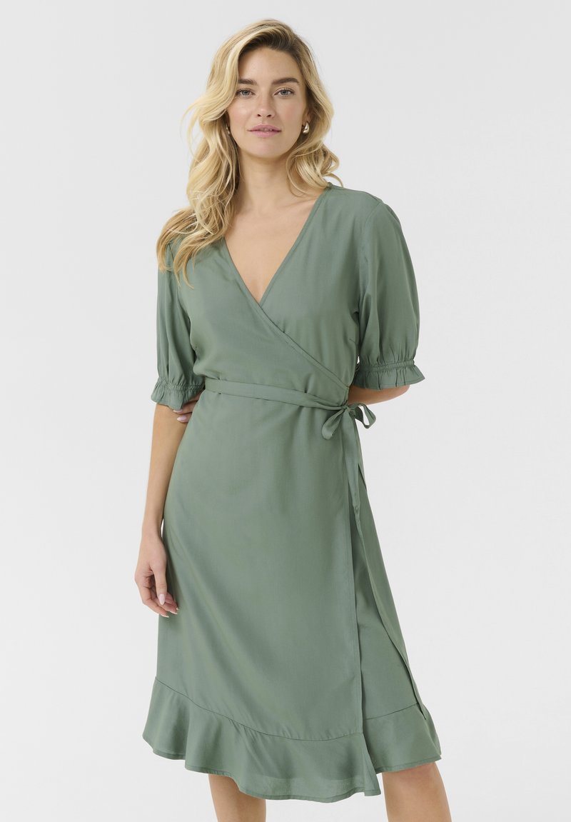 Sage green wrap dress with short puff sleeves, v-neckline, adjustable tie waist, and a flounced hem. Made of smooth, lightweight fabric.