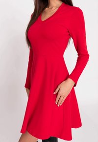 Rotes langärmliges Kleid mit V-Ausschnitt und schwingendem Rock, aus glattem Stoff gefertigt, mit tailliertem Oberteil und fließendem Saum.