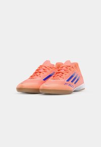 Scarpe da atletica di colore arancione brillante con accenti blu, design aerodinamico, parte superiore testurizzata e suola in gomma per una buona aderenza. Presentano lacci e marchio.