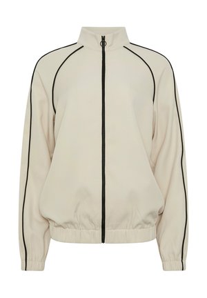 Chaqueta beige con cremallera, ribetes negros en las mangas, los costados y el cuello, puños y dobladillo elásticos, y tirador de cremallera en forma de anilla.