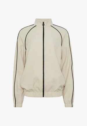 Chaqueta beige con cremallera, ribetes negros en las mangas, los costados y el cuello, puños y dobladillo elásticos, y tirador de cremallera en forma de anilla.