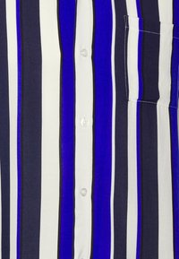 Camicia a maniche corte con righe verticali in navy, blu reale e bianco, con taschino sul petto e chiusura a bottoni. Tessuto morbido.