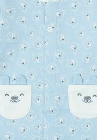 Tela azul clara con un patrón repetido de caras de oso, que incluye un bolsillo con una cara de oso bordada y orejas, aportando textura y detalle.