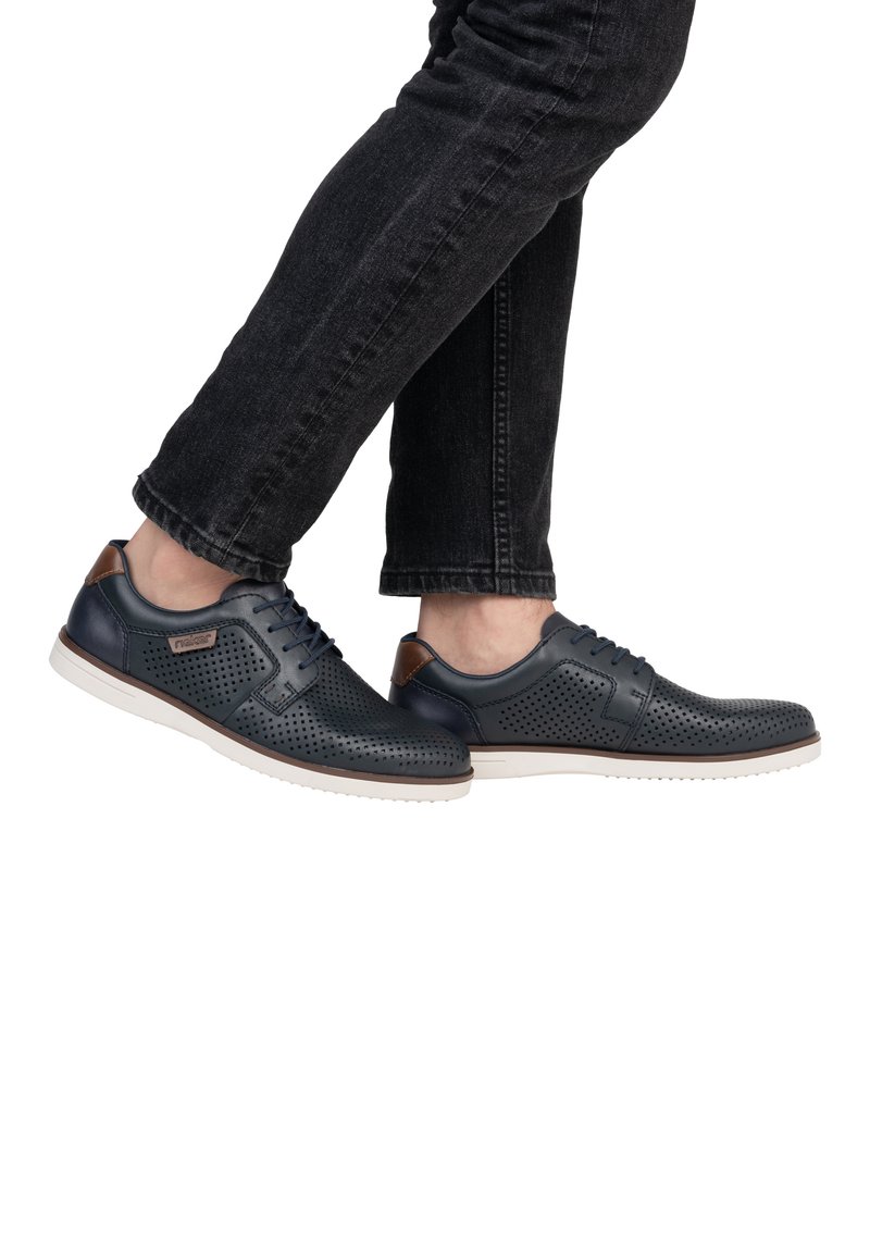Dark blue perforated leather shoes with brown accents and white rubber soles, featuring a classic lace-up design and textured surface.