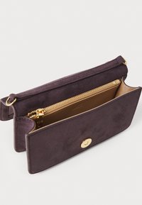 Μωβ σουέντ τσάντα φάκελος με κλείσιμο από χρυσό κουμπί και εσωτερική θήκη με φερμουάρ. Λείο εξωτερικό, μαλακή υφή, μινιμαλιστικός σχεδιασμός.