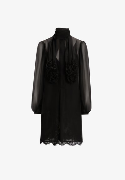 Robe en chiffon noir avec de longues manches, un col montant, et des accents floraux froncés à l'avant. Elle présente une finition en dentelle au niveau de l'ourlet.