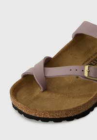 Light purple sandal with a cross-strap design, natural cork footbed, and a textured black sole. Features a gold-tone buckle closure.
