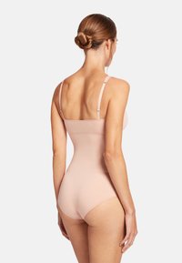 Body nudo con spalline regolabili, design senza cuciture e texture liscia, che esalta la figura con un taglio classico sui fianchi.