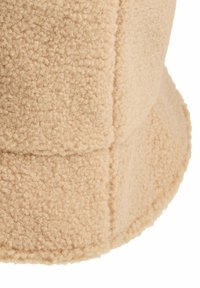Beige fleece bucket hat met een zachte, gestructureerde oppervlakte en een ronde rand. Heeft zichtbare stiksels en een gestructureerde vorm.