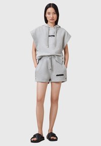 Hoodie en mélange de coton gris avec un design surdimensionné, cordon de serrage et détails de logo. Associé à un short gris assorti avec des pressions sur les côtés. Sandales noires.