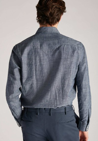 Achteraanzicht van een donkerblauwe, licht gestructureerde, langemouwen blouse met een puntkraag en subtiele schouderspanhalsdetails.