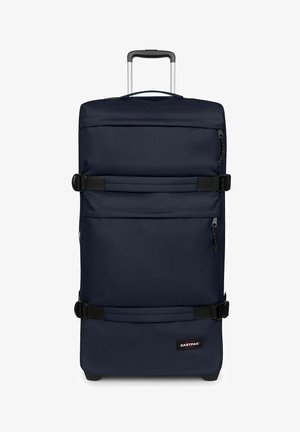 Valigia alta blu scuro con ruote, manico telescopico, due cinghie laterali, due tasche con cerniera e logo Eastpak nell'angolo anteriore inferiore.