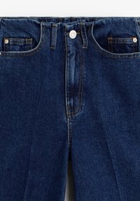 Mørkeblå denim jeans har en høj talje, fem lommer, kontrastsyning og en knaplukning foran.