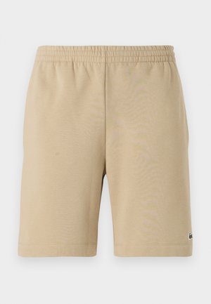 Beżowe bawełniane szorty z elastycznym paskiem w talii, o długości do kolan i małym logo po lewej stronie. Gładka faktura i prosty krój.