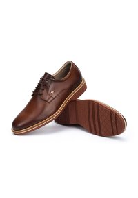 Chaussures en cuir brun avec une finition lisse, design à lacets et semelle en caoutchouc. Présente un logo discret et un surpiquage contrastant.