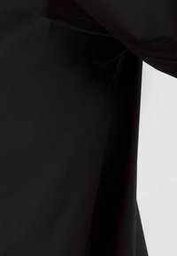 Čierna látka s hladkou textúrou, bez vzorov, a čistými líniami, ktorá predvádza minimalistickú estetiku bez ozdôb.